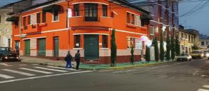 due persone in piedi davanti a un edificio arancione di Hostal California Star a Quito