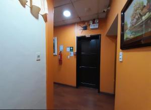 un corridoio con una porta nera su una parete arancione di Hostal California Star a Quito Altre 21 foto