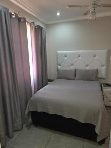 Lolly's Piece of Home في خليج ريتشاردز: غرفة نوم بسرير أبيض ونافذة