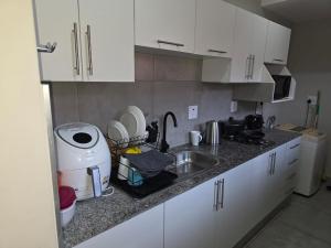 Lolly's Piece of Home في خليج ريتشاردز: مطبخ مع دواليب بيضاء ومغسلة وقمة كونتر +3 صور