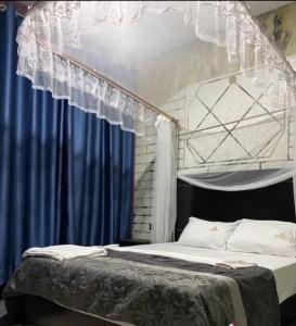 a bedroom with a bed with blue curtains at Javelin Palace Hotel in Kampala
