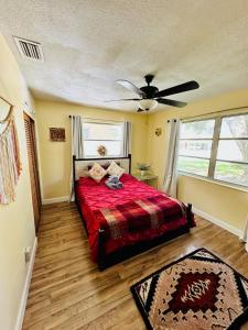 Schlafzimmer mit einem roten Bett und einem Deckenventilator in der Unterkunft Zen Den Beach House Bungalow in St Petersburg