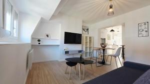 un salon blanc avec une table et une télévision dans l'établissement Le duplex de Belle Rade - proche centre et plage, à Dunkerque