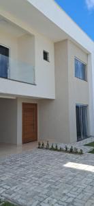 a large white house with a wooden door at Casa de Praia Nova, 3 quartos, 1 Suíte, com quintal privativo, em condomínio, muito bem Localizado in Porto Seguro