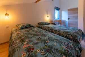 een slaapkamer met 2 bedden met een bloemenbed bij Charmant chalet, spacieux, proche du lac, vue sur la montagne in Gérardmer