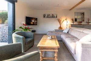 een woonkamer met een bank, twee stoelen en een tafel bij Charmant chalet, spacieux, proche du lac, vue sur la montagne in Gérardmer