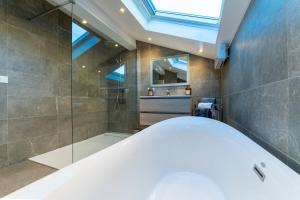 een badkamer met bad en douche met dakraam bij Charmant chalet, spacieux, proche du lac, vue sur la montagne in Gérardmer +32 foto's