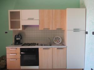 a kitchen with wooden cabinets and a white refrigerator at Ospitalità rurale La Svizzera in Agliè