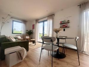 ein Wohnzimmer mit einer Couch und einem Tisch und Stühlen in der Unterkunft Escale Doullennaise - Appartement neuf avec terrasse in Doullens