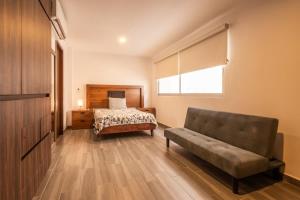 ein Schlafzimmer mit einem Bett und einer Couch und einem Fenster in der Unterkunft Amplio departamento con alberca in Los Cerritos