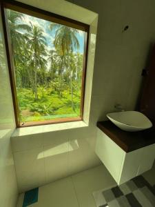 a bathroom with a window with a sink and palm trees at Forest Avenue - Kurunegala in Torayaya