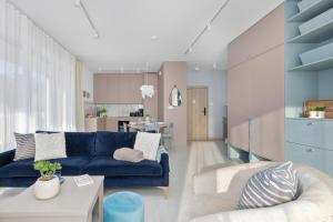 ein Wohnzimmer mit einer blauen Couch und einer Küche in der Unterkunft GREENERI PARK - Ambria Apartments in Świnoujście