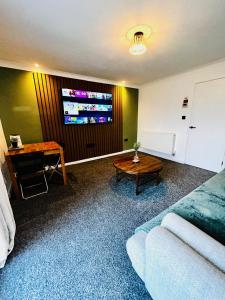 a living room with a couch and a table and a tv at Druridge Apartment in Blythe