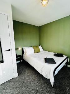 a bedroom with a white bed with a green wall at Druridge Apartment in Cowpen