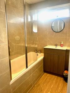 a bathroom with a shower and a tub and a sink at Druridge Apartment in Cowpen