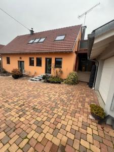 ein Haus mit einer gepflasterten Auffahrt davor in der Unterkunft Gite le Mamama, maison cosy au centre du village in Sommerau