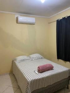 een bed met een roze kussen op de kamer bij Casa Aconchegante Odc in Olho D’Água do Casado