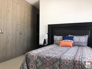 1 dormitorio con 1 cama grande con almohada naranja en Apartment with pool 3 blocks from the beach, en Isla Venados
