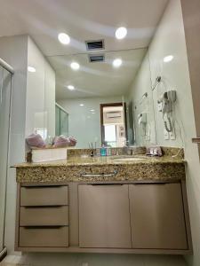 a bathroom with a sink and a large mirror at Tropical Executive Flat in Manaus