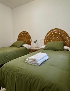 two beds with green sheets and towels on them at Apartamento a 10 minutos de Granada, Sierra Nevada a 35km, parking gratis in Alhendín