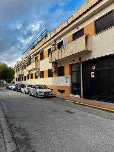 a building with cars parked on the side of a street at Apartamento a 10 minutos de Granada, Sierra Nevada a 35km, parking gratis in Alhendín