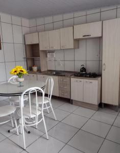 a kitchen with a table and white chairs and a table and a table and chairs at Pousada do Nico in São Gabriel