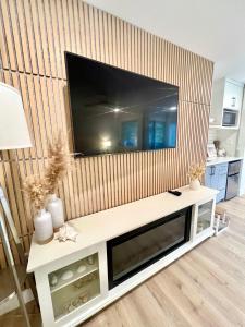 a living room with a large television on a wall at Low Tide Suite - Modern, Oceanside Suite with King Bed, Resort Pool & Hot Tub in Nanoose Bay