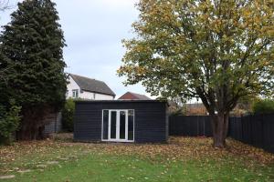 a small black shed in a yard with a tree at Large 4 bedroom Family let, Contractor, Corporate in Market Harborough