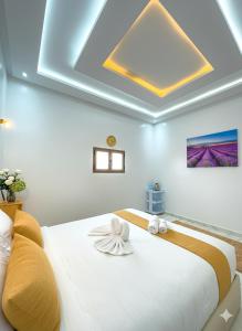 a bedroom with a large white bed with a ceiling at Hotel America Apartments in Dakhla
