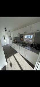 a kitchen with white cabinets and a window at Chalet Home Texel in De Koog