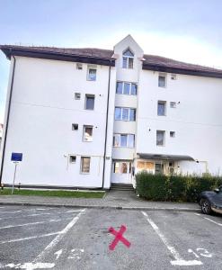 a large white building with a x in the parking lot at Apartament Booking Ultracentral in Bistriţa