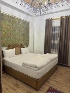 ein großes Bett in einem Zimmer mit einem Kronleuchter in der Unterkunft Central asia hotel in Muruntau