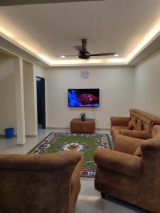 een woonkamer met 2 stoelen en een flatscreen-tv bij Home in Puchong Mahligai Achmed Homestay in Puchong