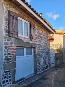 a stone house with two garage doors and a window at Le pat' toit in Aurec-sur-Loire