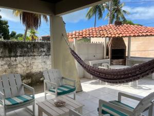 a hammock on a patio with chairs and a fireplace at Casa em Itamaracá - 70 metros da Praia in Itamaracá