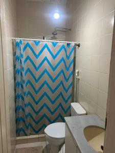 a bathroom with a shower curtain and a toilet at Casa em Itamaracá - 70 metros da Praia in Itamaracá