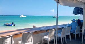 eine Bar mit Blick auf den Strand und ein Boot im Wasser in der Unterkunft Beach Lounge Punta Cana Aparthotel 1 in Punta Cana
