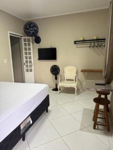 a bedroom with a bed and a chair and a tv at Bertioga litoral in Bertioga