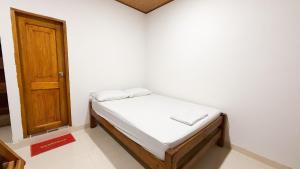 a small bed in a room with a wooden door at Apartamentos Datalu in Coveñas
