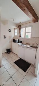 eine Küche mit weißen Schränken und einem Fliesenboden in der Unterkunft Montagnard RDC Hyper centre in Chartres