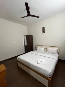 a bedroom with a white bed with a ceiling fan at Mount wave Pool villa in Wayanad