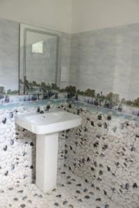 ein Badezimmer mit einem weißen Waschbecken und einem großen Spiegel in der Unterkunft The Papa Resort Ambuluwawa in Balatgomuwa