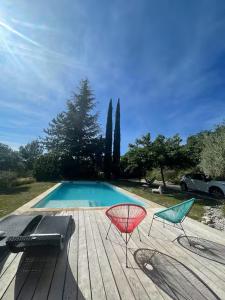 two chairs sitting on a deck next to a swimming pool at Studio calme 15 min Aix en Provence in Éguilles