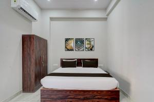 a bedroom with a bed and a wooden cabinet at Collection O Kesar Crossway Jaipur Formerly Laxmi Palace in Jaipur