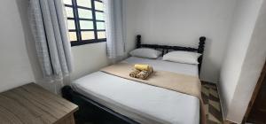 two twin beds in a room with a window at Hospedaria Oliveira - São Thomé das Letras in São Thomé das Letras