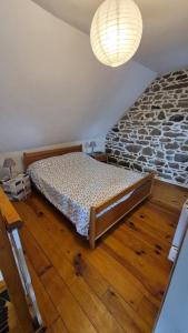 a bedroom with a bed and a stone wall at Les gîtes de la salamandre in Callac