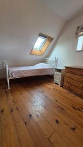 a bedroom with a bed and a window and a wooden floor at Les gîtes de la salamandre in Callac