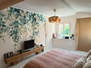 a bedroom with a tv and a flower wallpaper at La parenthèse Brognonnaise in Brognon