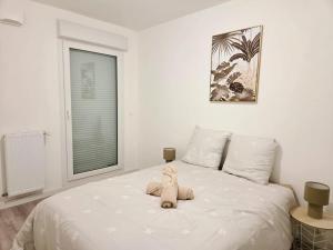 Ein Stofftier sitzt auf einem Bett in einem Schlafzimmer in der Unterkunft Le Chaleureux in Annemasse