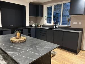 eine Küche mit schwarzen Schränken und einer schwarzen Arbeitsplatte in der Unterkunft Cottage in Holmfirth Centre in Holmfirth